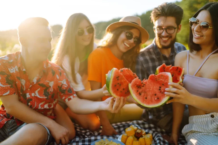 Grupo de amigos compartiendo sandía en un picnic al aire libre